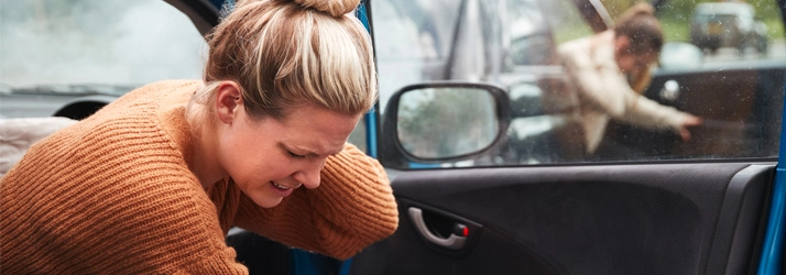 Chiropractic Orlando FL Car Accident Woman getting out of a car after an accident, holding her neck.